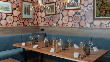 A restaurant interior with a wooden table set for dining, blue upholstered seating, and a wall adorned with a log pattern.