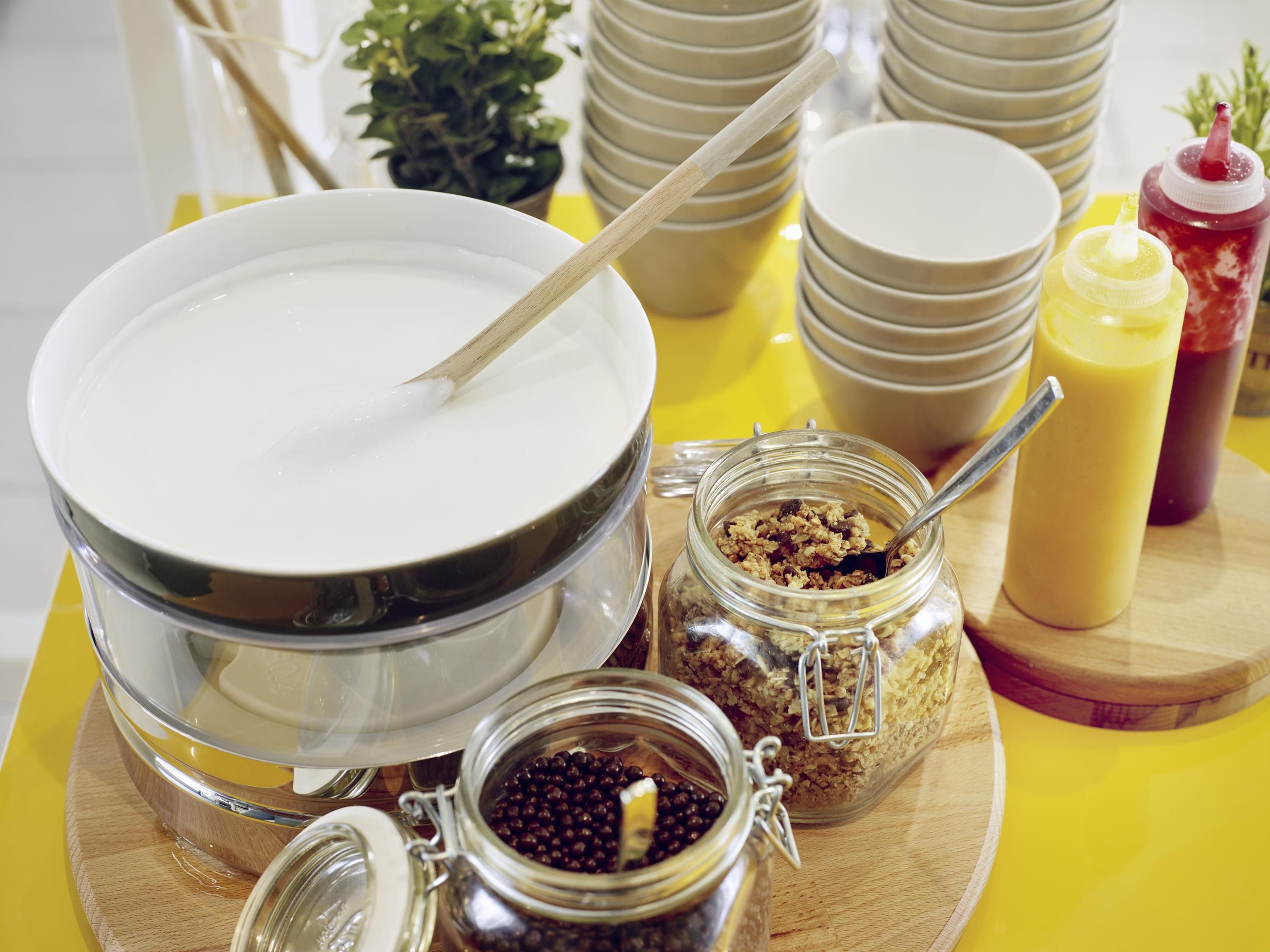 A breakfast buffet setup with bowls, jars of condiments, and a spoon.