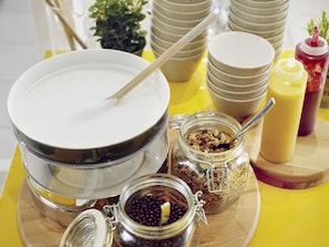 Un buffet de petit-déjeuner avec des bols, des pots de condiments et une cuillère.