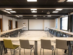 Un salón de conferencias con una larga mesa, varias sillas y una pantalla para proyector.