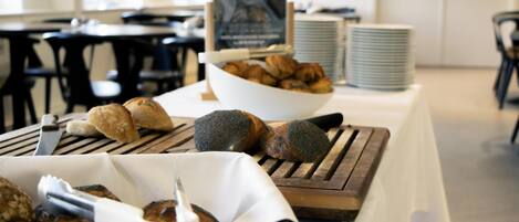 A buffet table with various baked goods and a sign in the background.