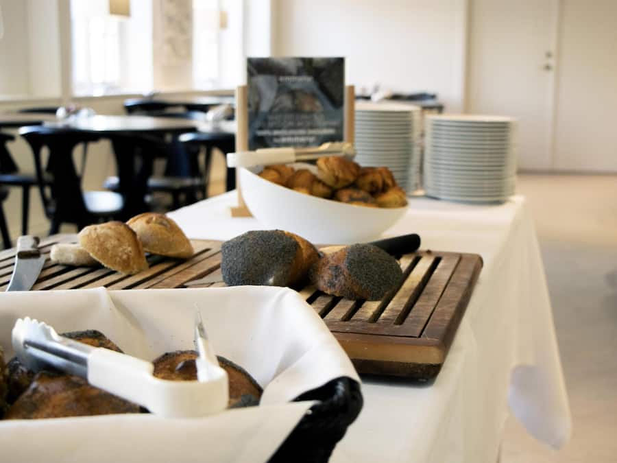 A buffet table with various baked goods and a sign in the background.
