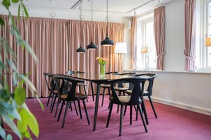 A conference room with a round table, black chairs, and a vase of flowers.
