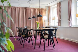 A conference room with a round table, black chairs, and a vase of flowers.