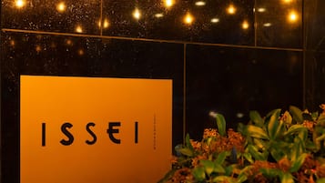 Een bord met de tekst 'ISSEI' en 'COPENHAGEN' op een oranje achtergrond, met een plant op de voorgrond.