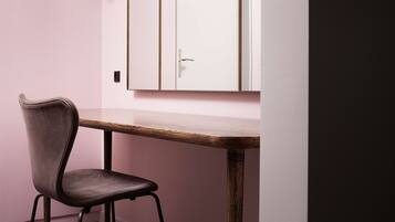 A chair and a table in a room with a pink wall and a white cabinet.