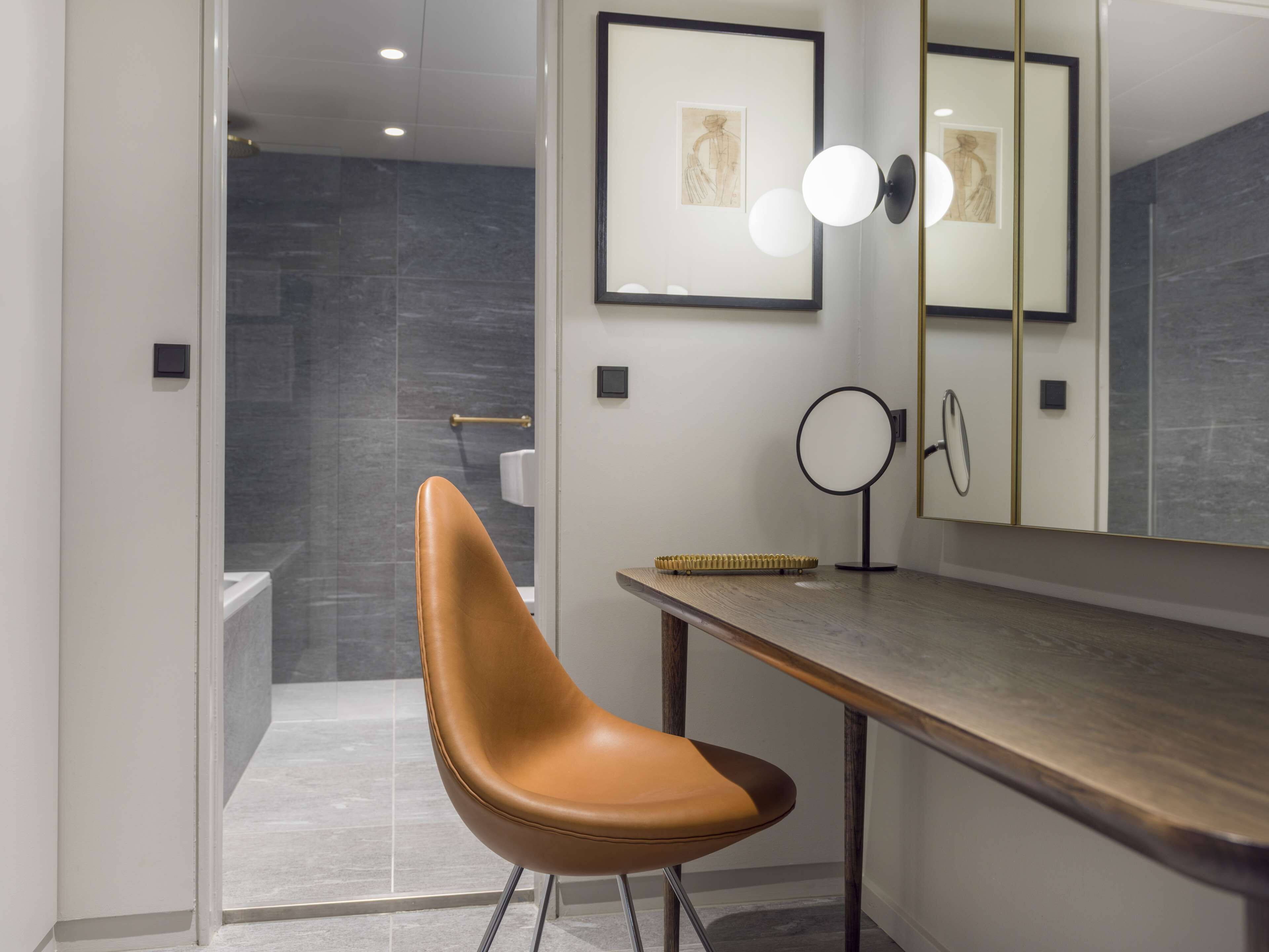 Une salle de bain moderne avec une douche, un meuble-lavabo avec un miroir et une chaise.