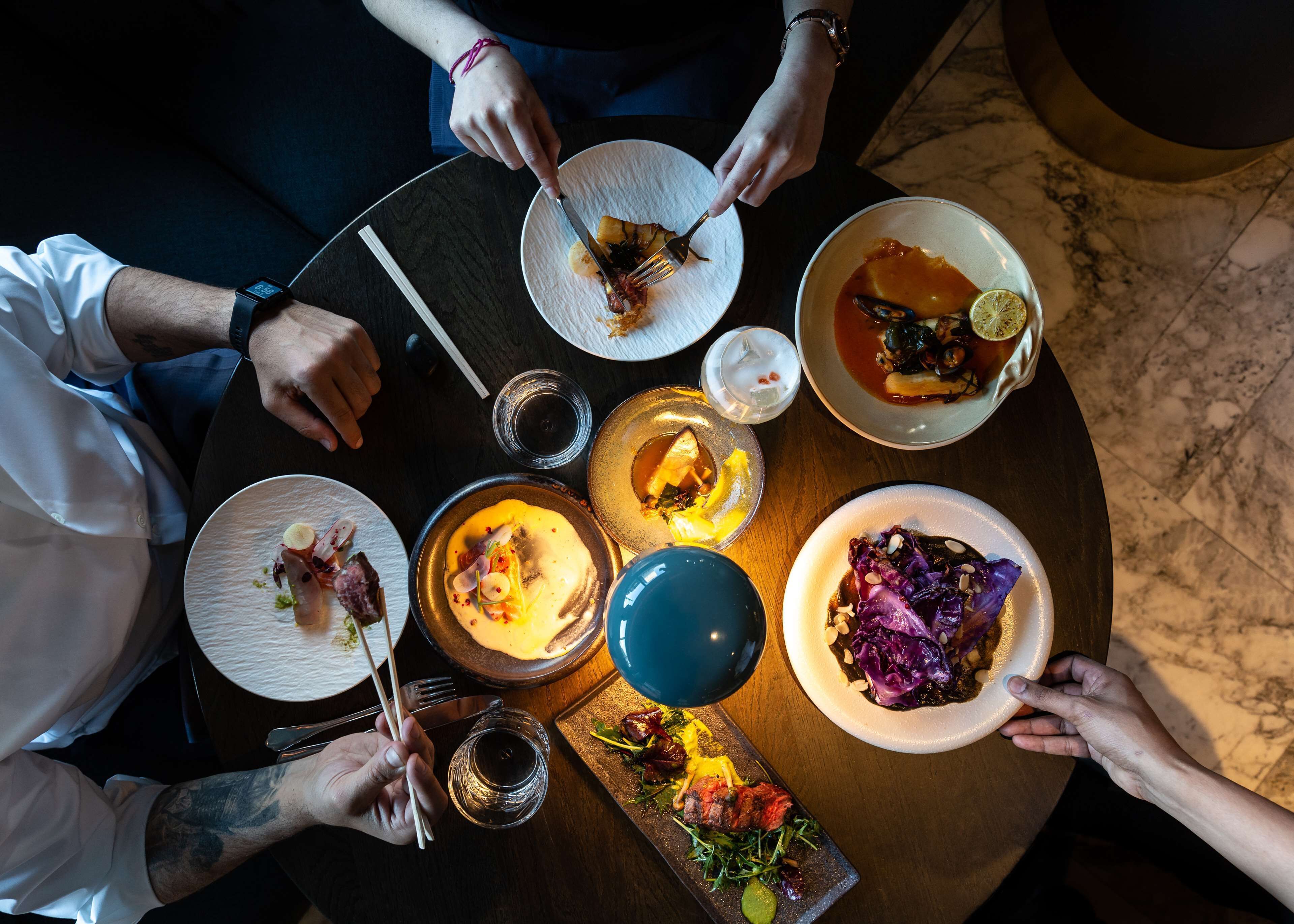 A group of people dining at a round table with various dishes.
