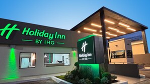 Un bâtiment Holiday Inn, appartenant au groupe IHG, doté d’un design moderne, de grandes fenêtres et d’une entrée bien éclairée.