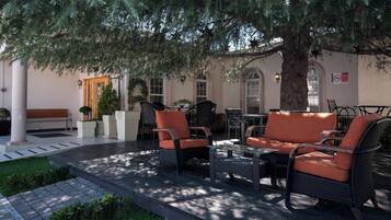 Un espacio al aire libre con mobiliario de mimbre, un banco y una mesa.