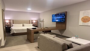 Une chambre d’hôtel équipée d’un lit, d’un bureau, d’une télévision, d’un canapé et d’une table basse.