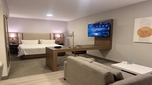 A hotel room with a bed, a desk, a television, a sofa, and a coffee table. - Holiday Inn & Suites Chihuahua Expo (Chihuahua)