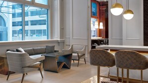 A modern hotel lobby with a seating area, large windows, and a bar. - Le Meridien St. Louis Downtown (St. Louis)