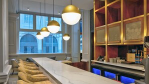 A modern bar area with a long counter, multiple seating options, and pendant lighting. - Le Meridien St. Louis Downtown (St. Louis)