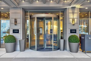 A revolving door with glass panels, two potted plants, and signage for 'MERIDEN' and 'VALET'. - Le Meridien St. Louis Downtown (St. Louis)