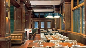 A spacious dining area with wooden paneling, multiple tables set for dining, and large windows providing natural light. - Le Meridien St. Louis Downtown (St. Louis)