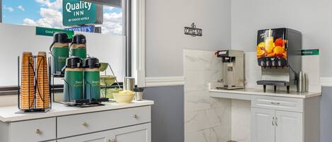 A hotel kitchen with coffee machines, a coffee bar, and a view of the sky.