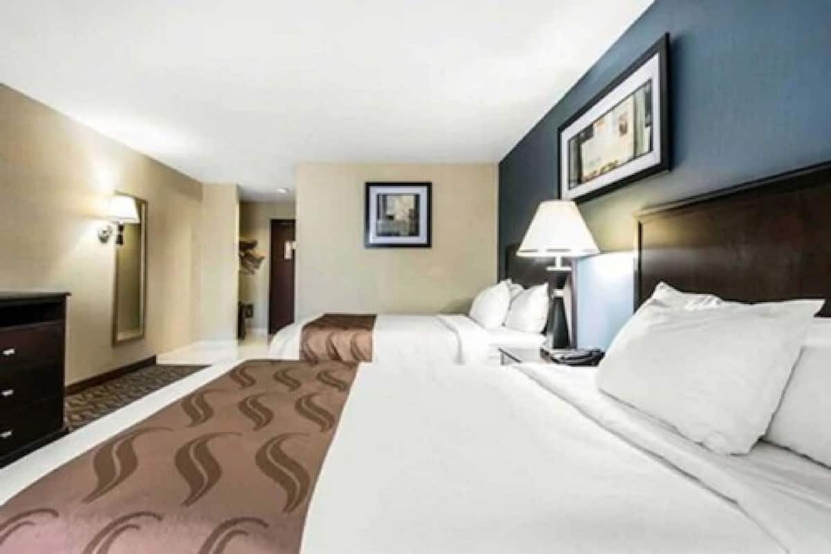 Une chambre d’hôtel avec un lit, une table de chevet, une lampe et un tableau encadré au mur.