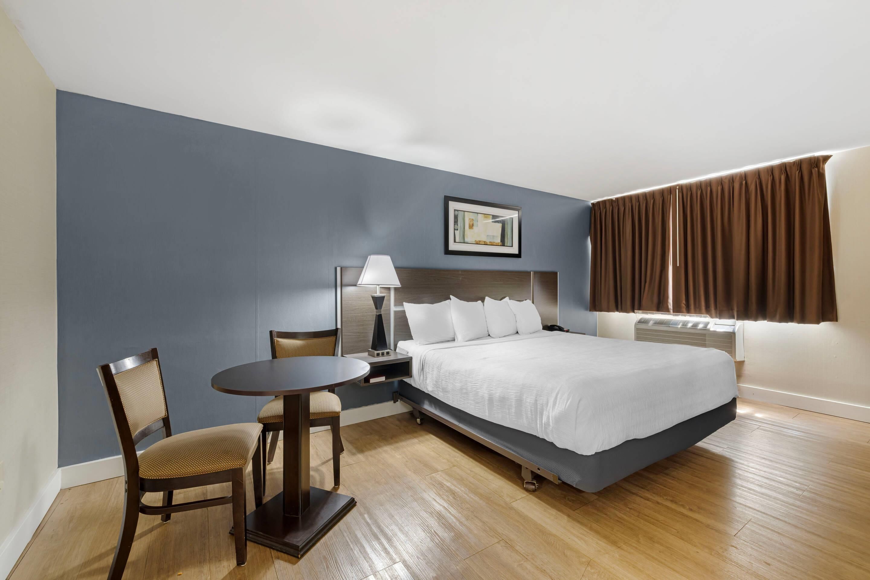 Ein Hotelzimmer mit Bett, Schreibtisch, Stuhl, Lampe und einem Bild an der Wand.