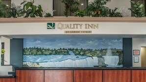 A reception desk with a mural of a waterfall and forest. - Quality Inn - Niagara Falls Blvd (Niagara Falls)