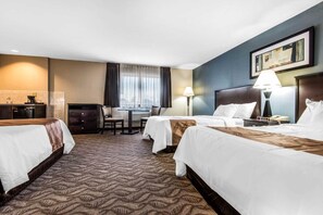 Camera d'albergo con due letti, una scrivania, una sedia, una lampada e un quadro appeso al muro.