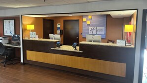 Un comptoir d’accueil d’hôtel équipé d’un ordinateur, d’un téléphone et d’une enseigne indiquant « Holiday Inn Express ».