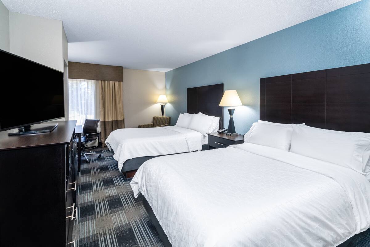A hotel room with two beds, a desk with a TV, and two bedside lamps.