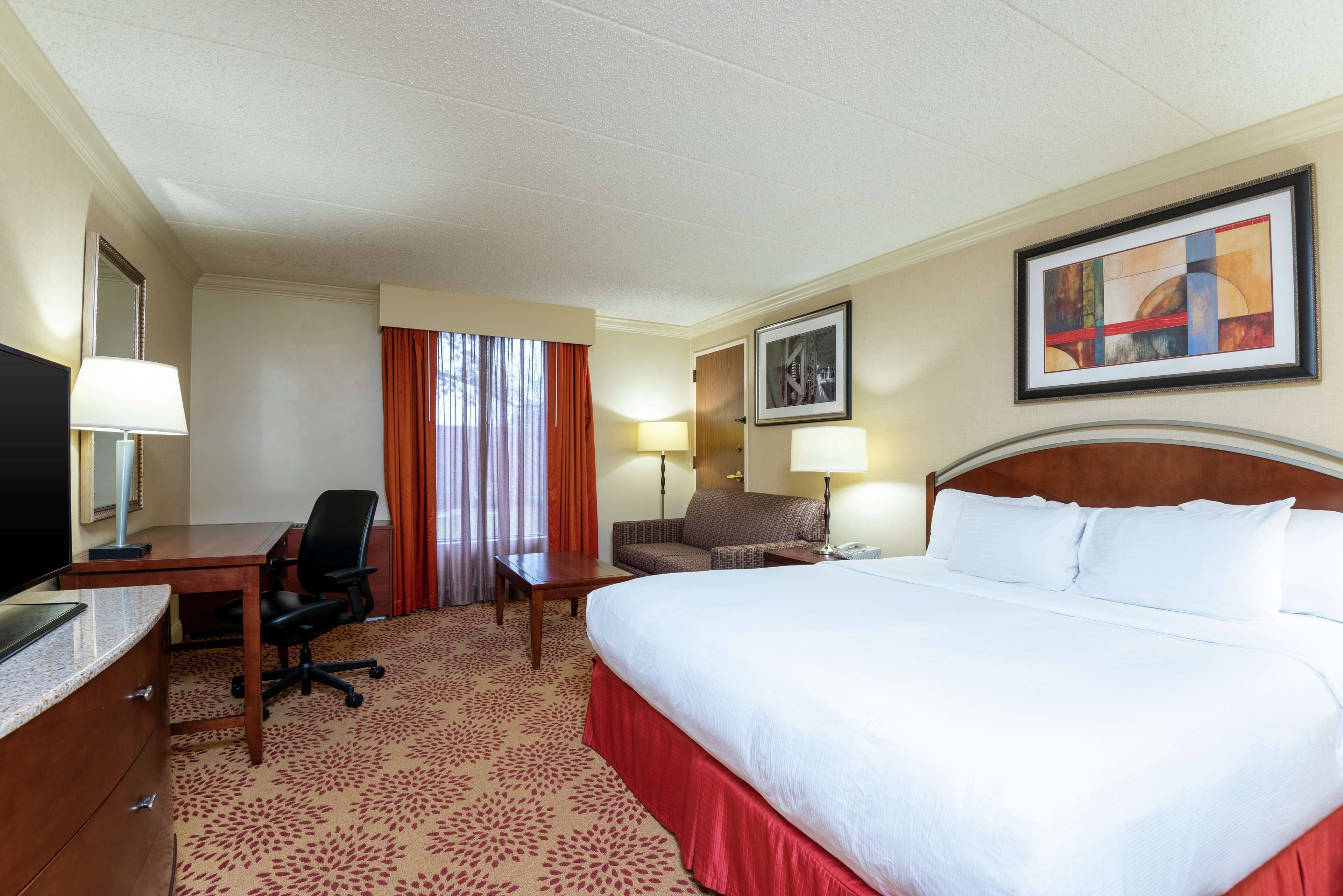 Een hotelkamer met een groot bed, een bureau met stoel, een televisie en twee lampen.