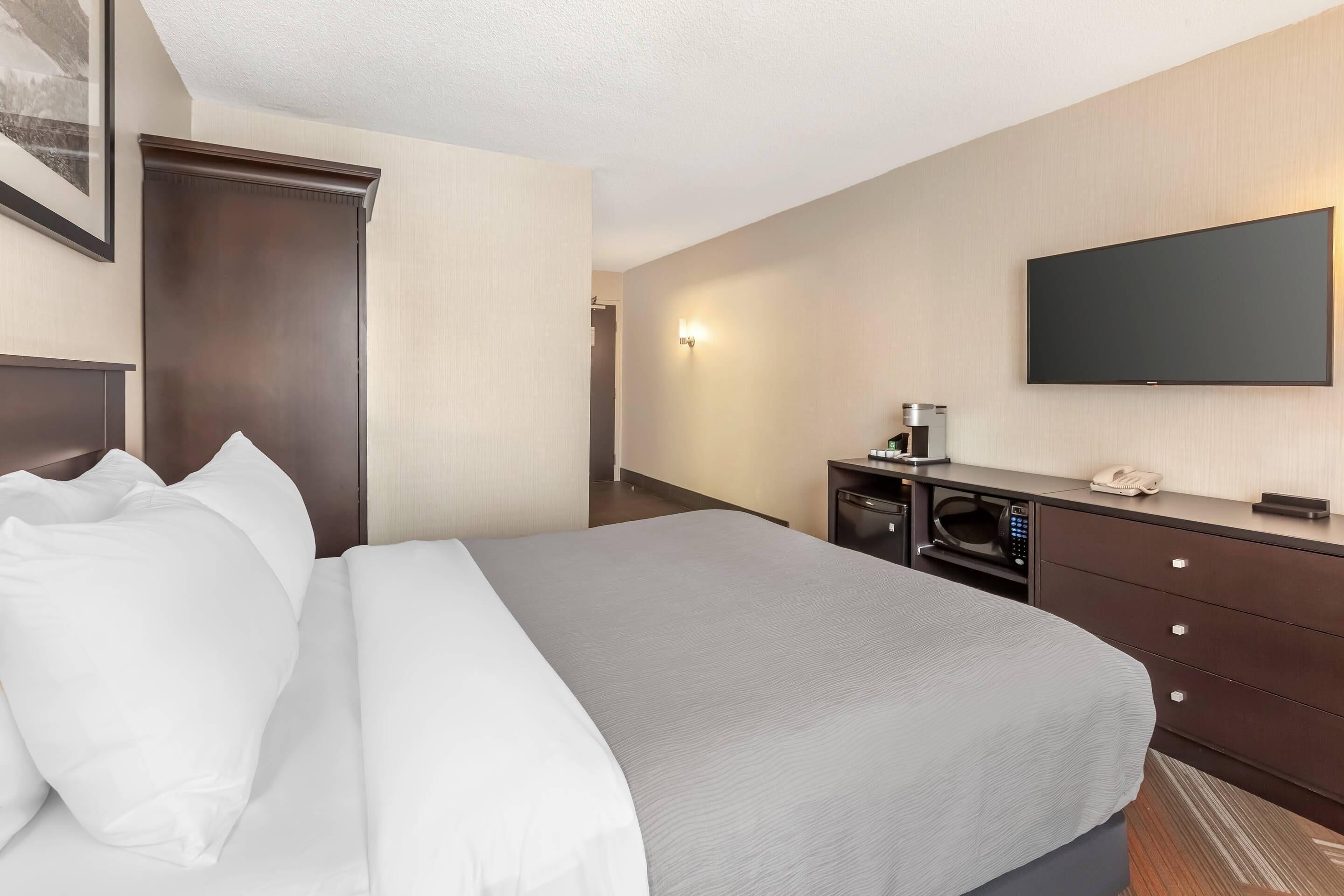 Habitación de hotel con cama, televisión de pantalla plana, cafetera y microondas.