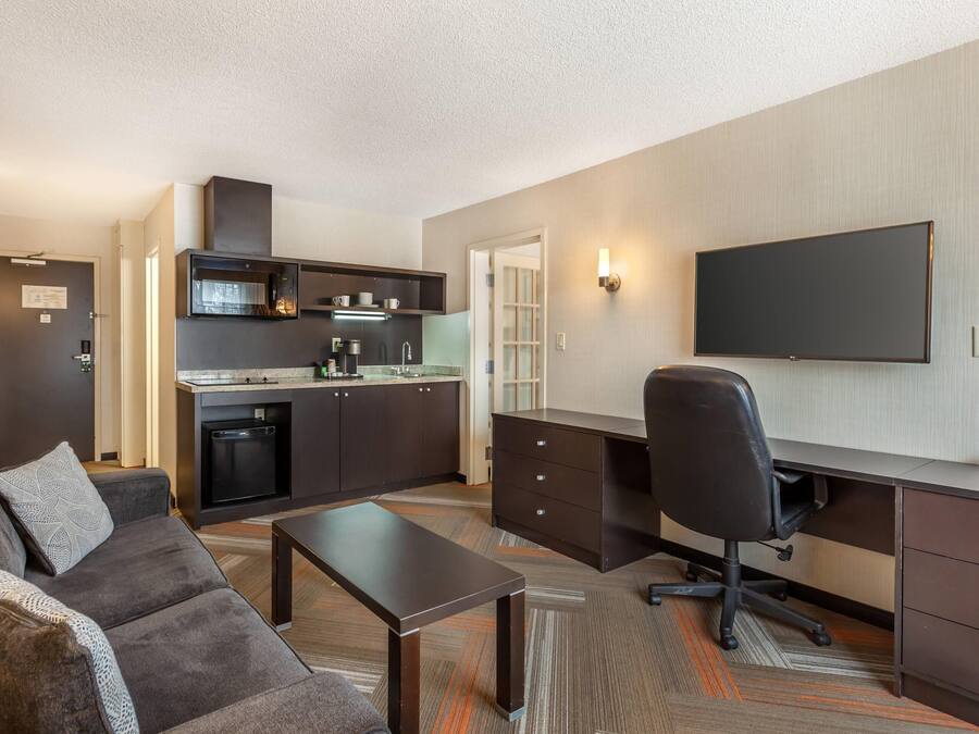 Un espacio habitable compacto con kitchenette, televisor de pantalla plana, sofá, mesa de centro y escritorio con silla.