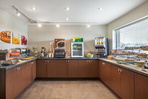 A modern kitchen with a coffee station, a refrigerator, and a breakfast bar. - Quality Hotel (Burlington)