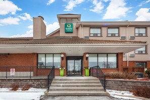 A hotel with a 'Quality Hotel' sign, a brick facade, large windows, and a covered entrance.
