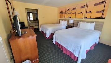 A hotel room with two beds, a desk with a computer, a TV, and a trash bin.