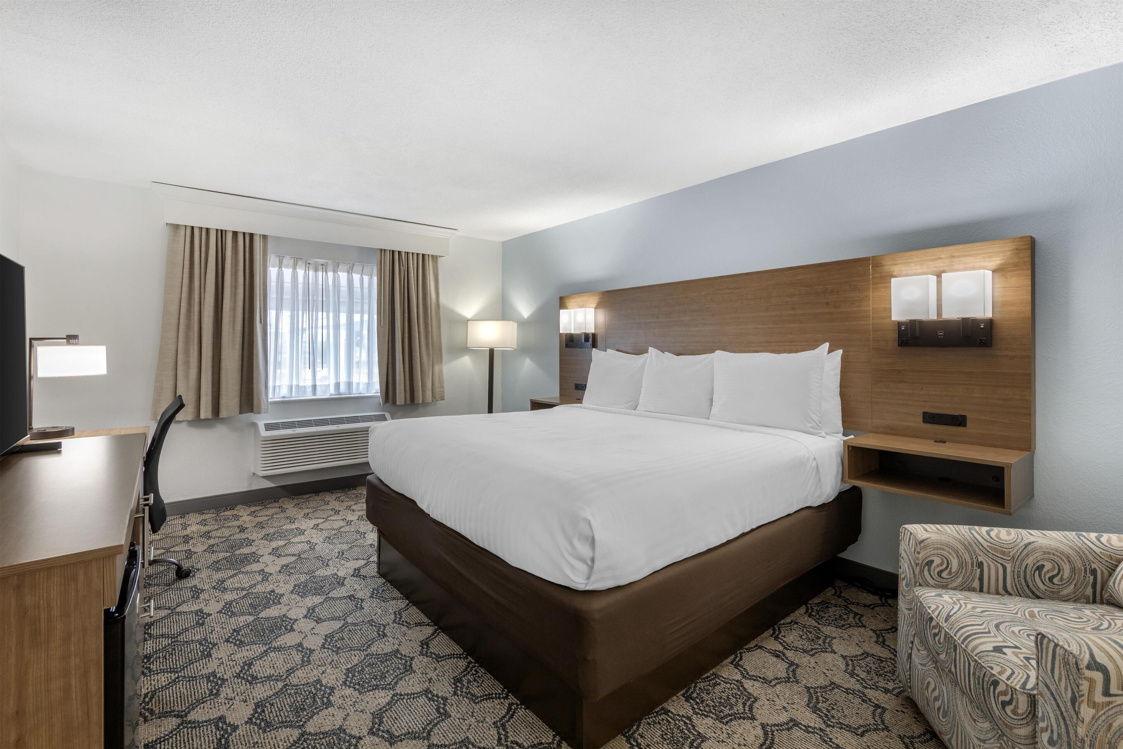 Een hotelkamer met een groot bed, een bureau, een stoel en een televisie.