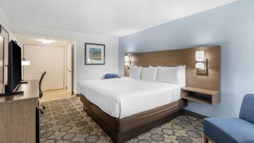 A hotel room with a large bed, a desk, a chair, and a television.