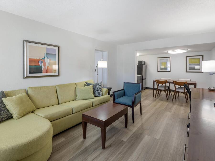 Una sala de estar moderna con sofá, sillón, mesa de centro y comedor con sillas y una mesa.