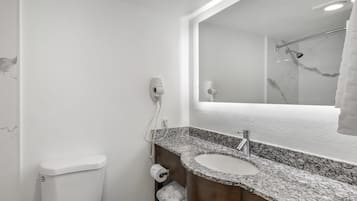 A bathroom with a white toilet, a sink with a marble countertop, and a mirror above the sink.
