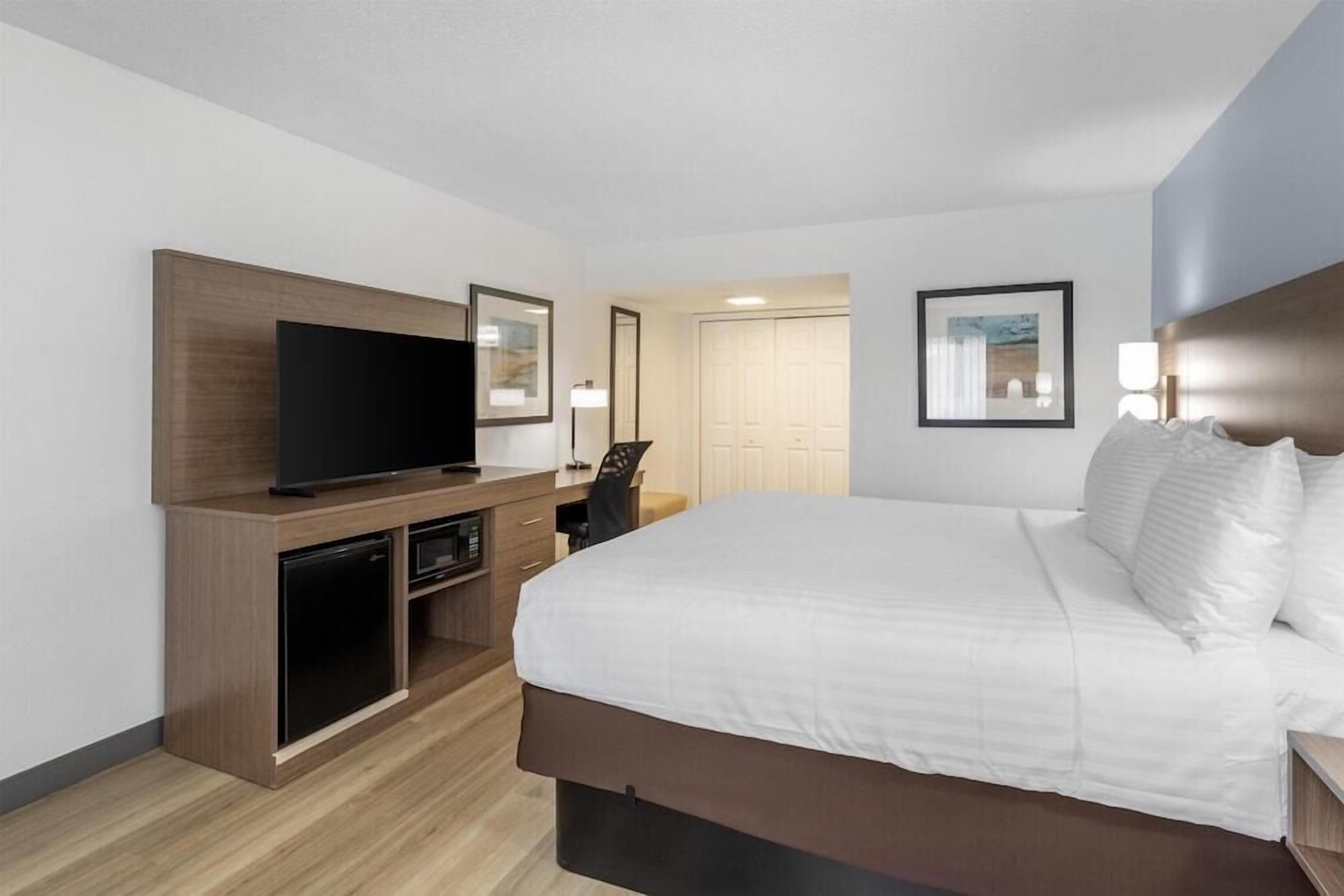Ein Hotelzimmer mit Bett, Fernseher, Schreibtisch mit Stuhl und Kleiderschrank.