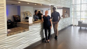 Un espace d'accueil doté d'un mur aux motifs ondulés, d'un comptoir avec un menu et d'une fenêtre offrant une vue agréable.