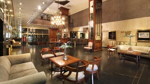 Un vestíbulo amplio con techo alto, candelabros y una variedad de arreglos de asientos, incluyendo sofás y sillones.
