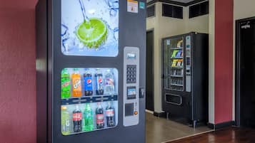 A vending machine with a selection of beverages, including sodas and juices, in a hallway.