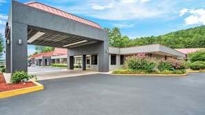 A modern building with a covered entrance, a parking lot, and surrounding greenery. - Red Roof Inn Hot Springs (Hot Springs)