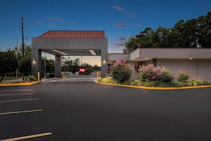 A parking lot with a building entrance, a covered area, and a sign that reads "Best Value." - Red Roof Inn Hot Springs (Hot Springs)
