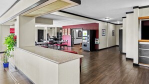 Un hall d’hôtel spacieux comprenant un comptoir d’accueil, un espace repas et un distributeur automatique de boissons fraîches.