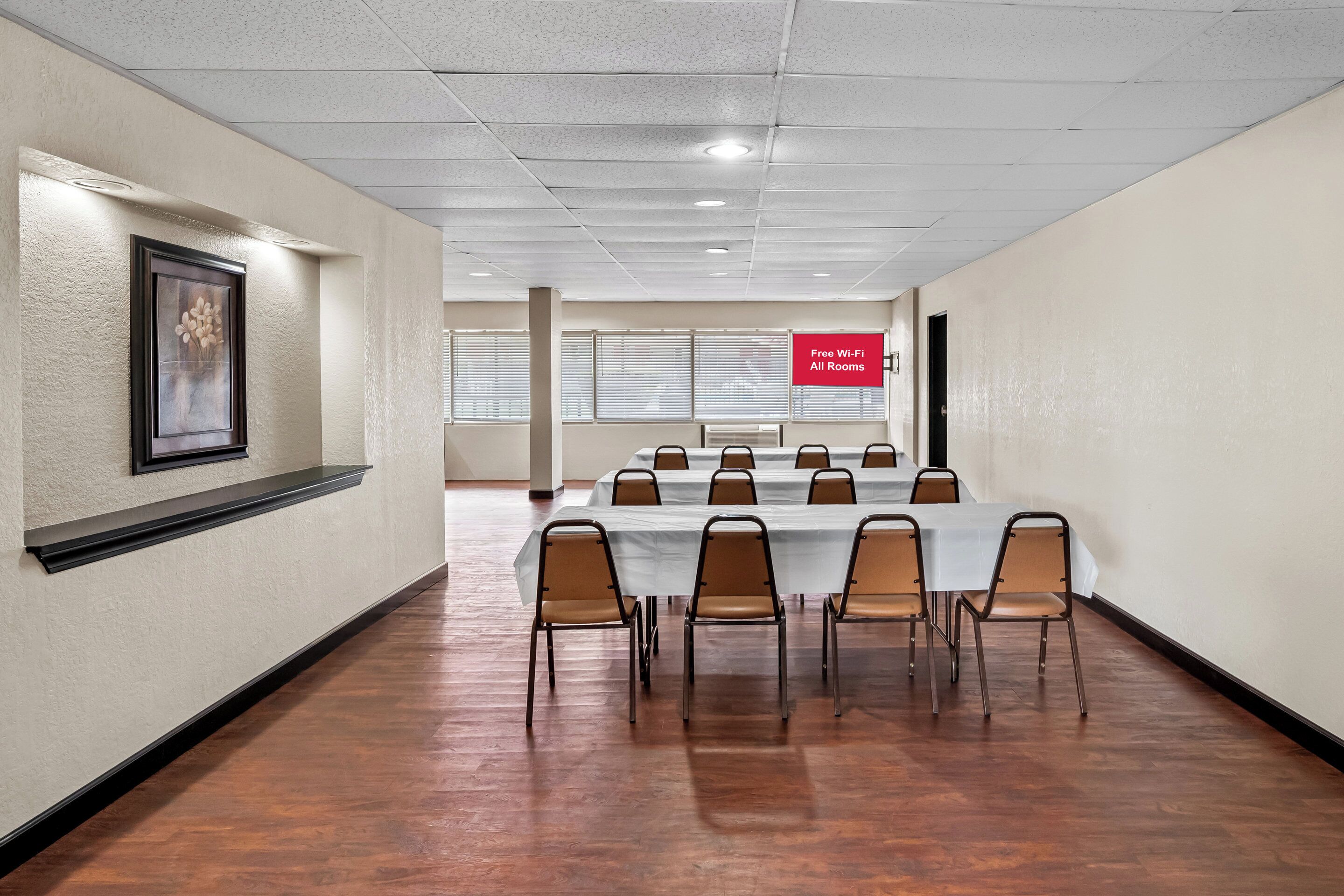 A conference room with a long table and chairs, a framed artwork on the wall, and a sign indicating free Wi-Fi in all rooms.