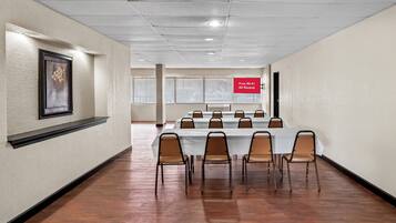 A conference room with a long table and chairs, a framed artwork on the wall, and a sign indicating free Wi-Fi in all rooms.