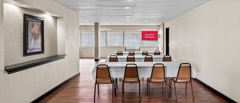 A conference room with a long table and chairs, a framed artwork on the wall, and a sign indicating free Wi-Fi in all rooms.