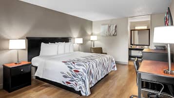 A hotel room with a bed, bedside tables, a desk, and a chair.