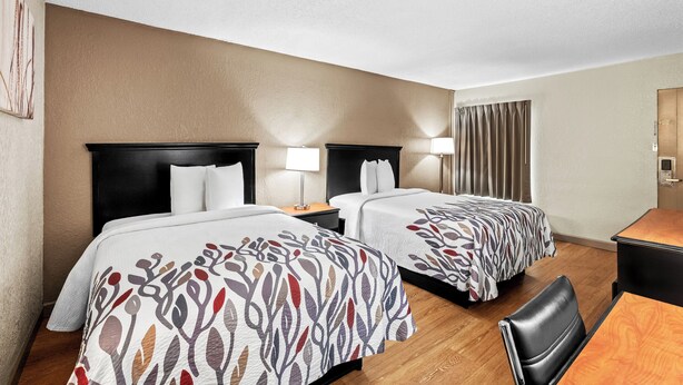A hotel room with two beds, a desk, and a chair. - Red Roof Inn Hot Springs (Hot Springs)