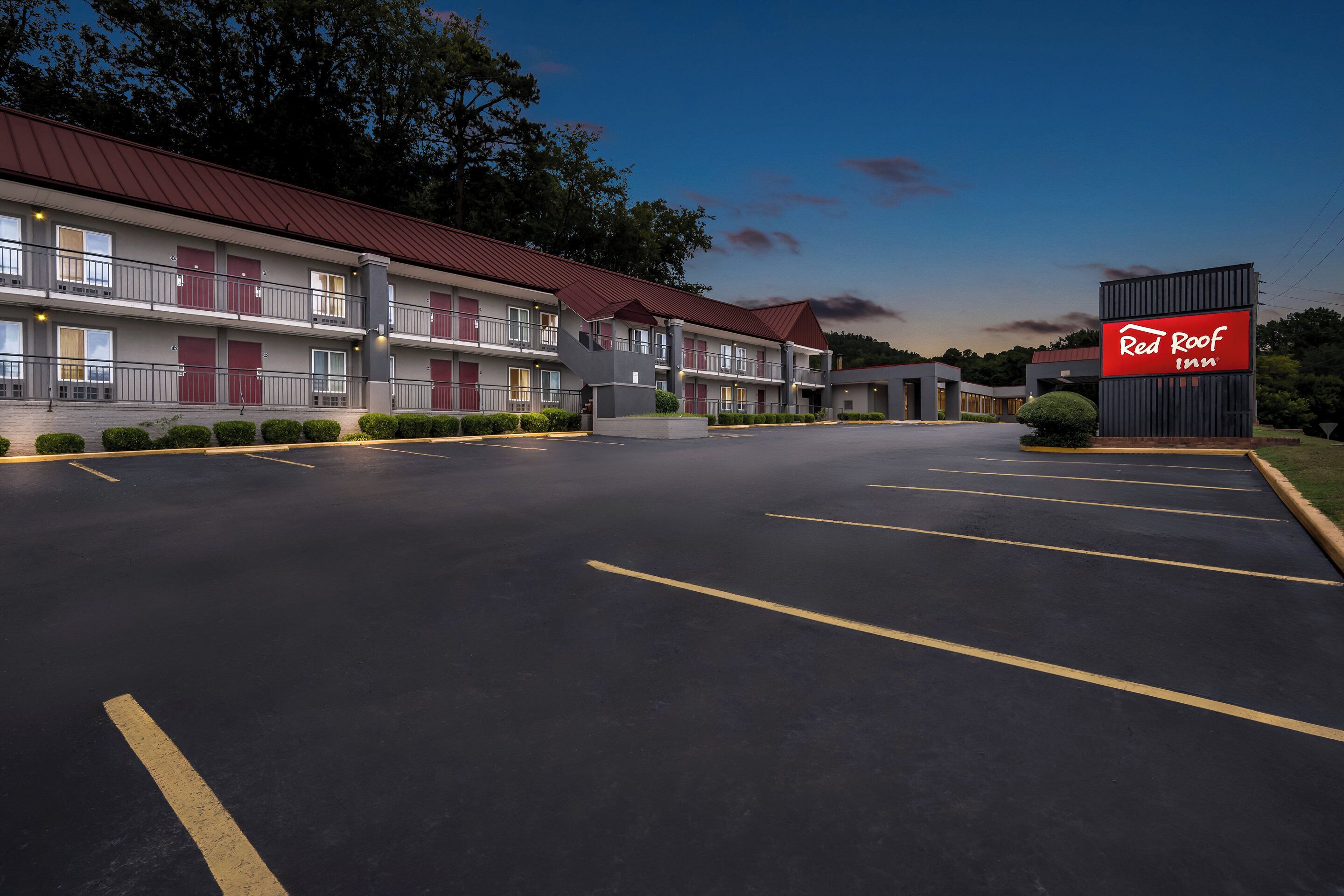 A Red Roof Inn with a two-story building, a parking lot, and a well-maintained lawn.